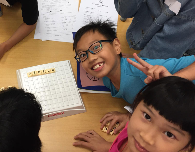 參與英語故事工作坊的小朋友玩拼字遊戲，舉著勝利手勢，笑得十分開心。